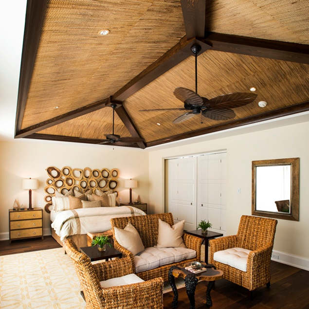 Chambre avec plafond habillé d’un revêtement Phillip Jeffries effet bois et mobilier en rotin